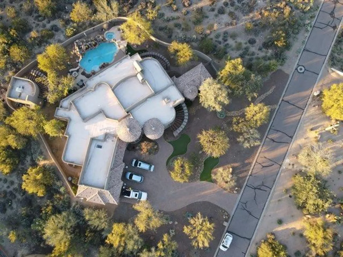 A luxurious swimming pool is surrounded by a pristine landscaped garden and the stylish architecture of the house. The driveway and parked cars hint at group arrival. The scene radiates relaxation and sociability, ideal for unwinding after a day outdoors.