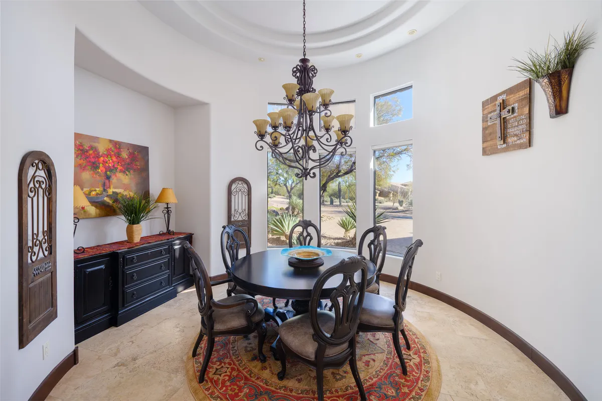 An inviting dining area with a round table set beneath an elegant chandelier. The space is decorated with tasteful artwork and offers window views, making it ideal for family meals, holiday gatherings, or casual conversations.
